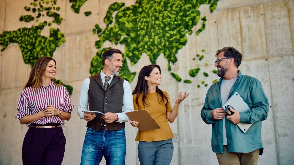 Gruppe von Mitarbeitern im Gespräch vor einer bepflanzten Wand zum Thema Nachhaltigkeit